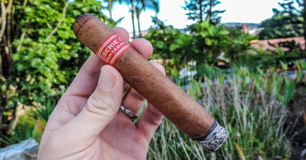 Hand holding a Partagás cigar