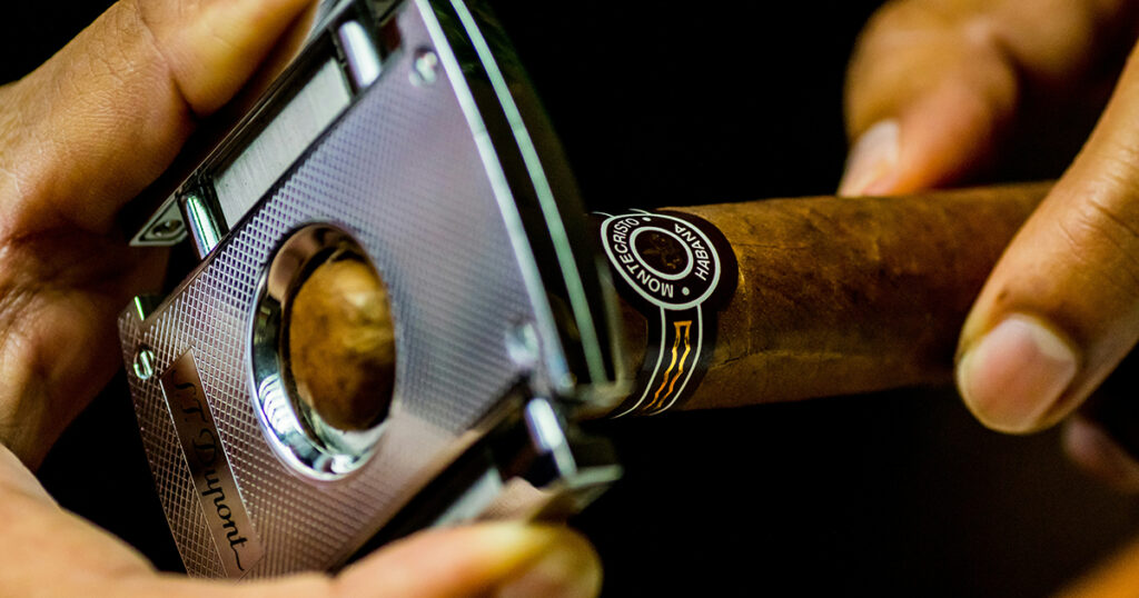 Close up of fingers cutting a montecristo cigar